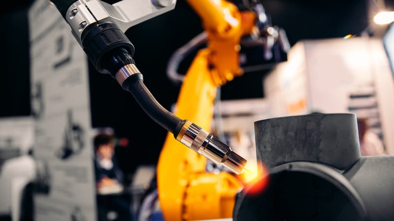 Robot arm welding metal pipe.