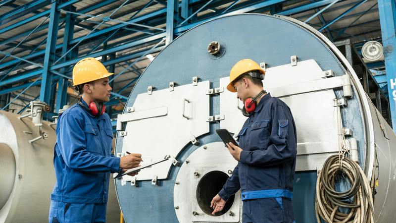 Two technicians perform a boiler inspection.