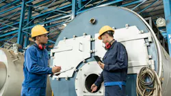 Two technicians perform a boiler inspection.