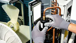 HVAC technician wearing gloves repairs an air conditioning unit's internal components.